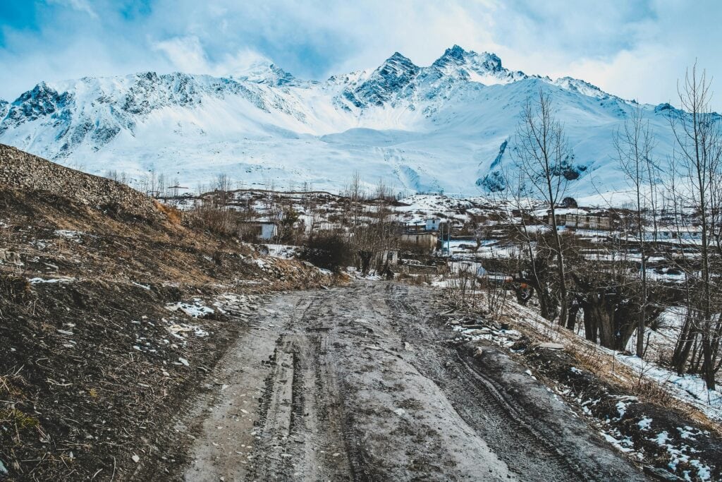Explore the stunning winter landscape of Muktinath, Nepal, with snow-covered mountains and a serene village setting.