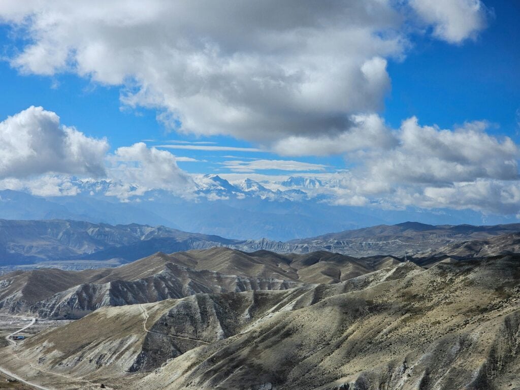 Breathtaking aerial view of the Mustang region in Nepal, showcasing mountainous terrain and a clear blue sky.